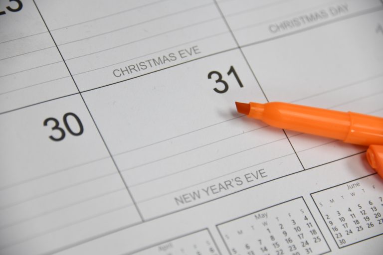 Photo of an orange highlighter resting on a calendar page.